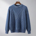 Pull bleu jean à col rond, torsades et losange en relief, suspendu à un cintre en bois