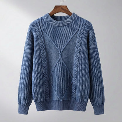 Pull bleu jean à col rond, torsades et losange en relief, suspendu à un cintre en bois