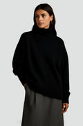Pull col roulé noir en maille fine, porté avec une jupe grise