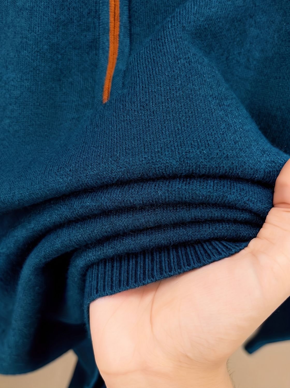 Gros plan sur la maille et l'ourlet côtelé d'un pull bleu pétrole