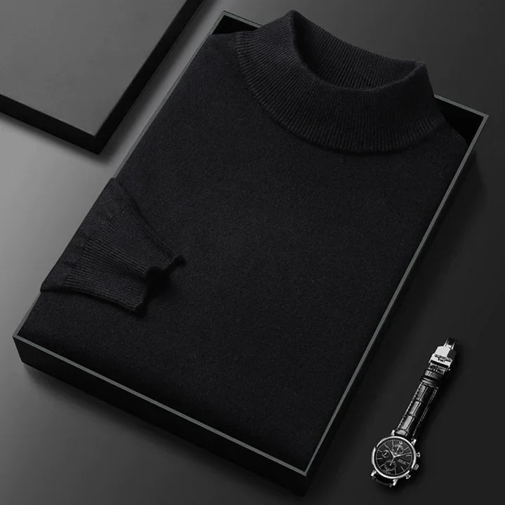 Pull noir à col montant côtelé, plié dans un écrin noir avec une montre posée à côté