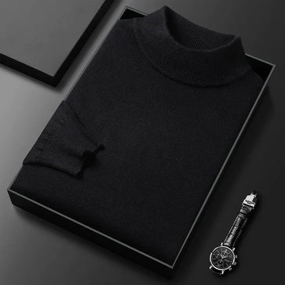 Pull noir à col montant côtelé, plié dans un écrin noir avec une montre posée à côté