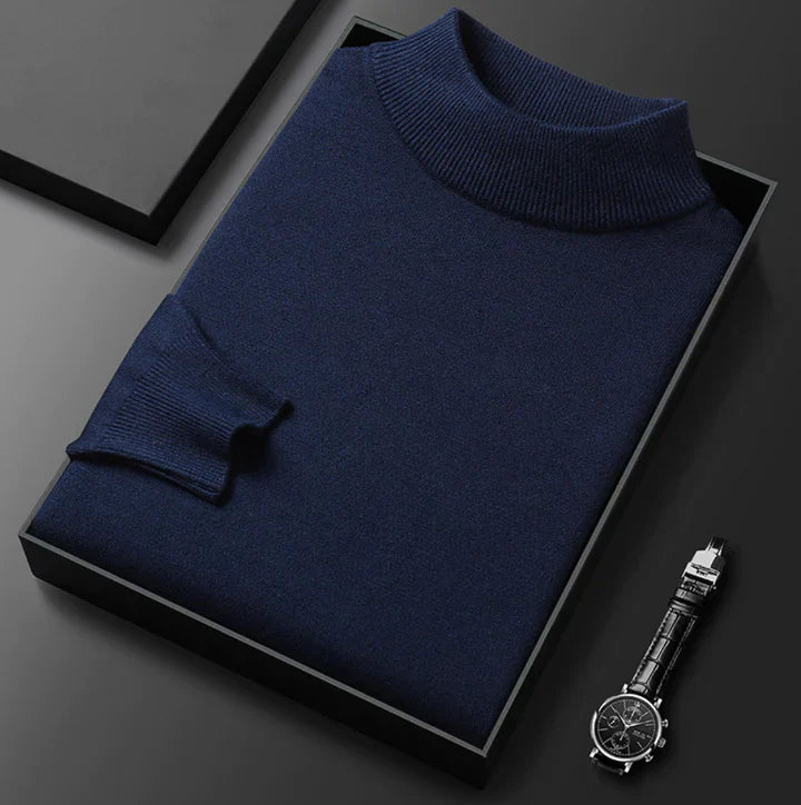 Pull bleu marine à col montant, plié dans un coffret noir, montre posée à côté