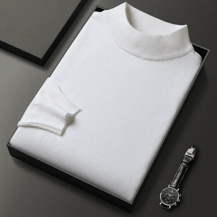 Pull blanc à col montant, plié dans un coffret noir à côté d'une montre-bracelet