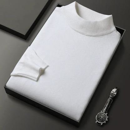 Pull blanc à col montant, plié dans un coffret noir à côté d'une montre-bracelet