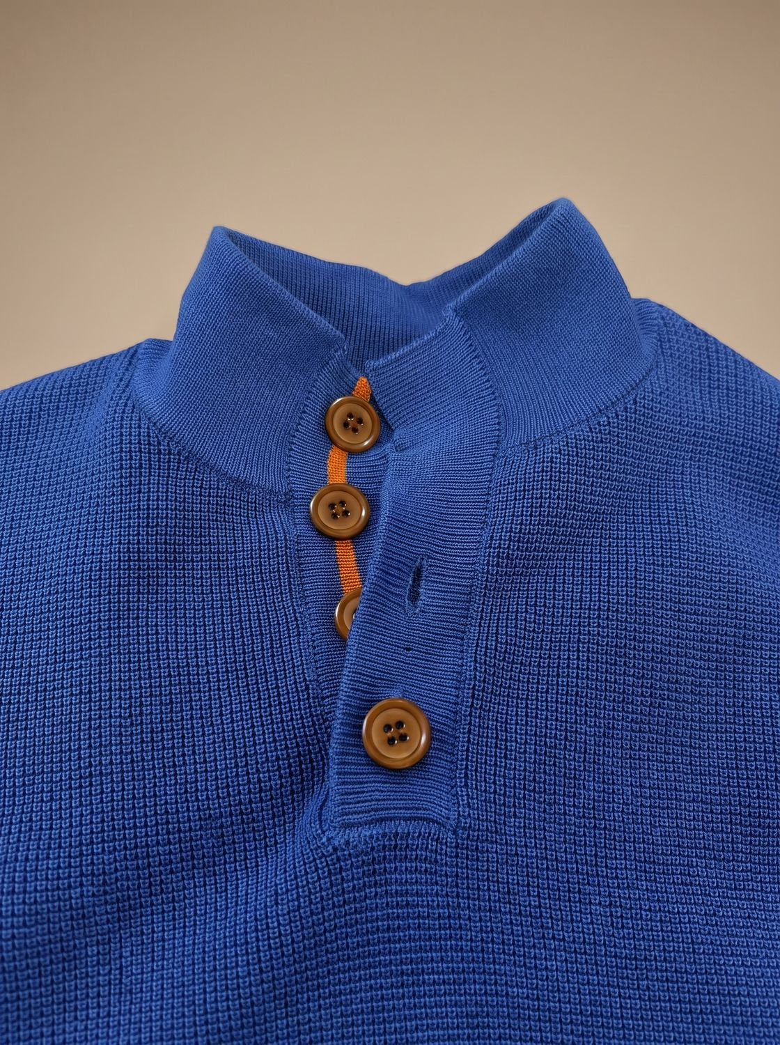 Détail du col montant boutonné du pull bleu roi