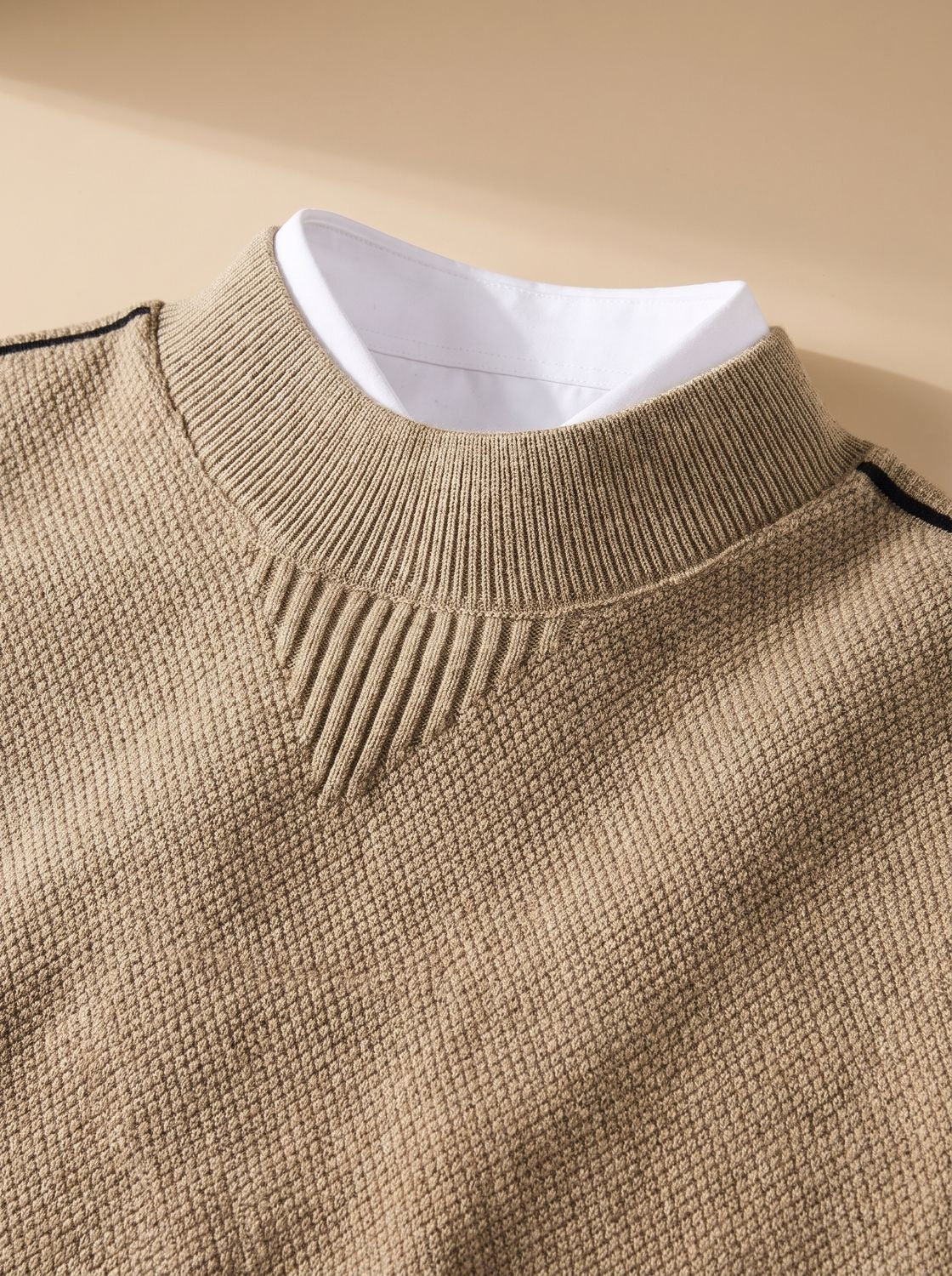 Col montant côtelé du pull jacquard camel porté sur une chemise