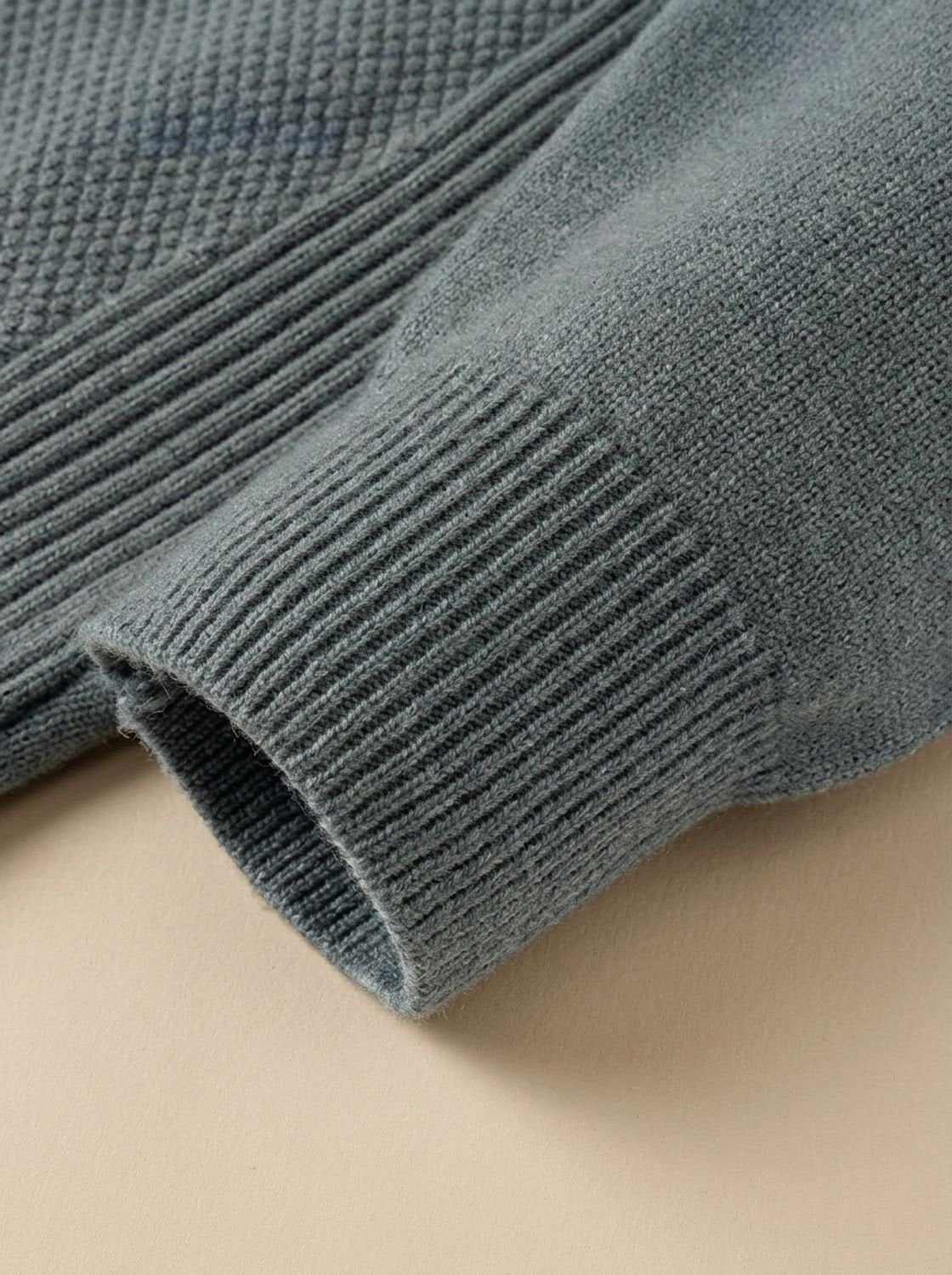 Poignet côtelé et maille jacquard du pull vert de gris en gros plan