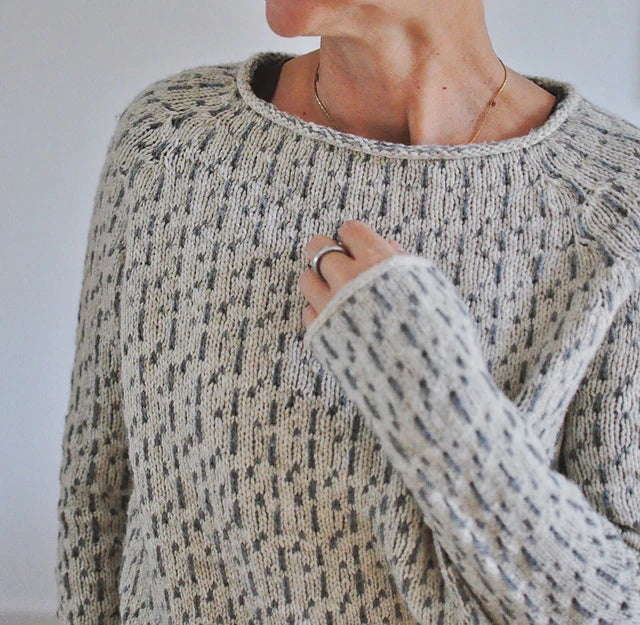 Détail du col roulotté et de la maille texturée d'un pull beige