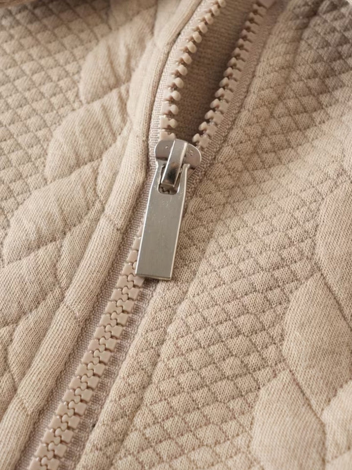 Pull torsadé col zippé en crème avec fermeture éclair argent, détail textile torsadé