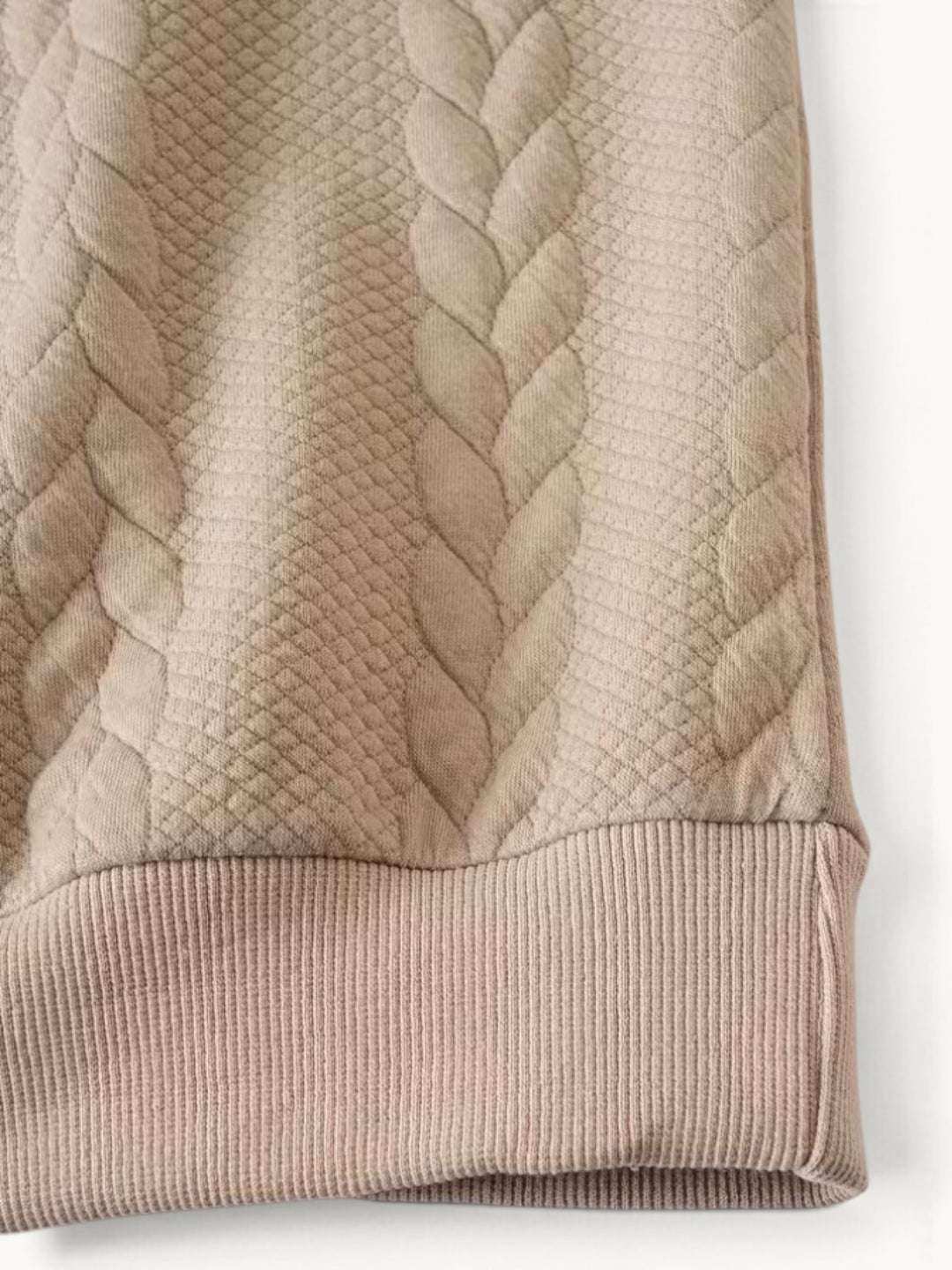 Pull torsadé beige clair, détail de la manche avec côtes tricotées