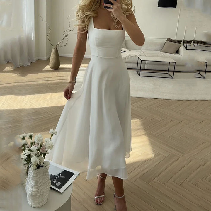 Robe midi blanche à col carré portée dans un intérieur clair