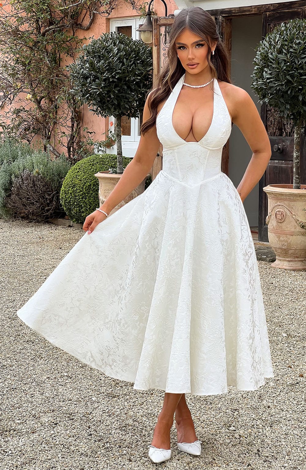 Robe midi dos nu blanche portée dans un jardin, jupe évasée