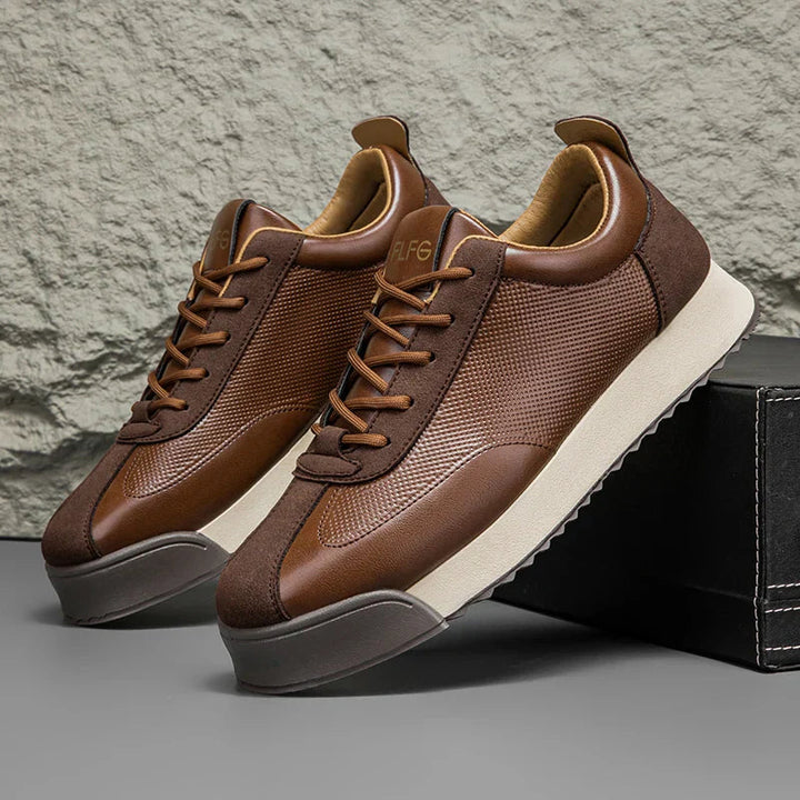 Paire de sneakers marron devant un mur en pierre brute, semelle crème épaisse