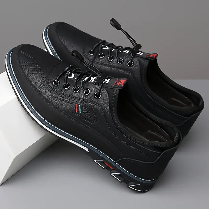 Paire de sneakers en cuir noir en appui sur un socle blanc, lacets élastiques