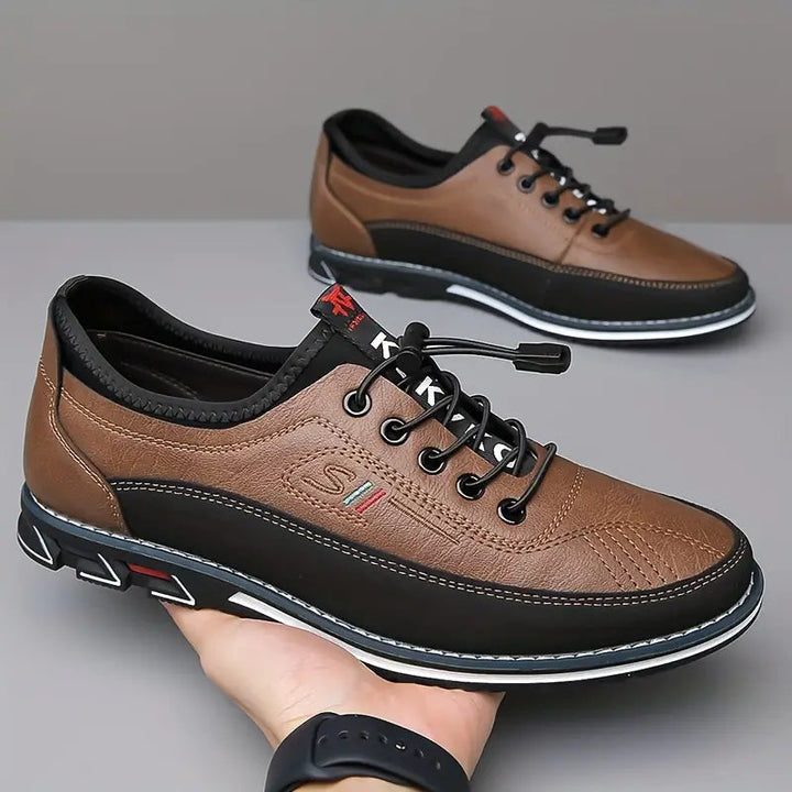 Main tenant une sneaker marron et noir, la seconde floue en arrière-plan