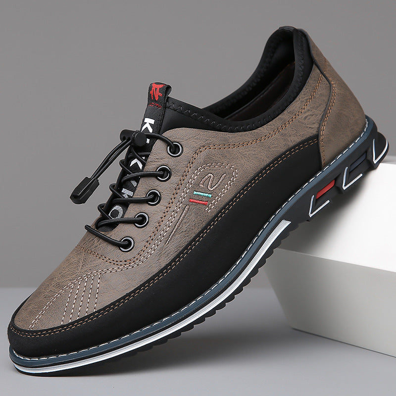 Paire de sneakers gris taupe et noir en appui sur un socle blanc