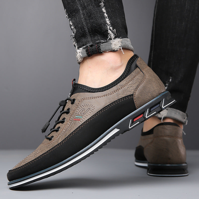 Sneakers gris taupe portées avec un jean noir, en marche sur fond gris