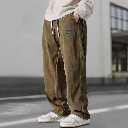 Pantalon en velours côtelé brun kaki, étiquette noire à la hanche et jambe droite