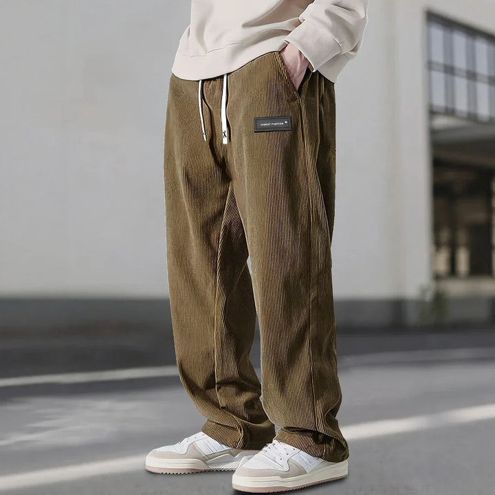 Pantalon en velours côtelé brun kaki, étiquette noire à la hanche et jambe droite