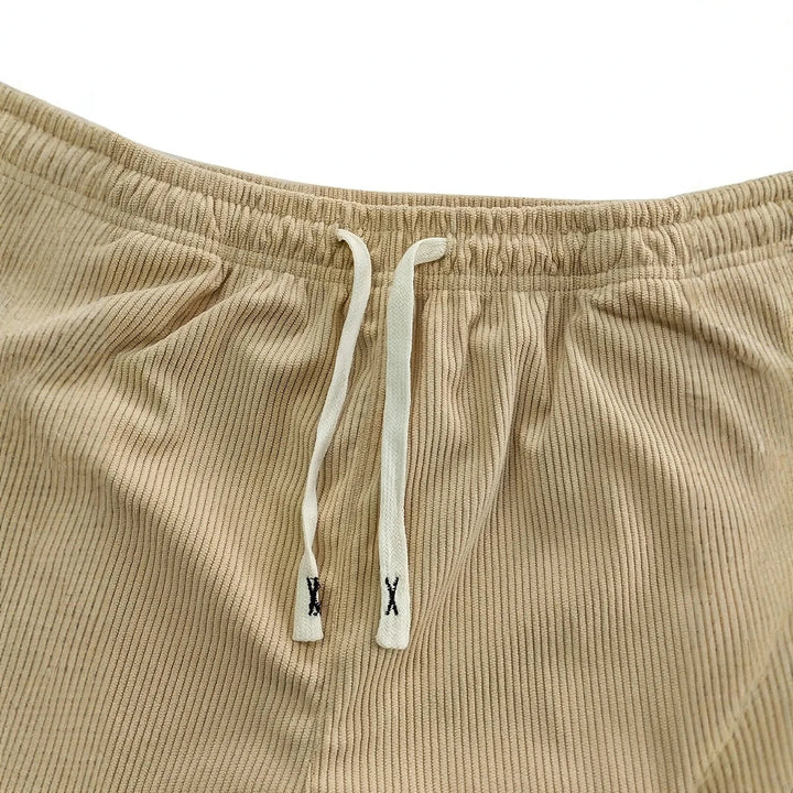 Gros plan sur la taille élastique beige et son cordon plat écru à embouts