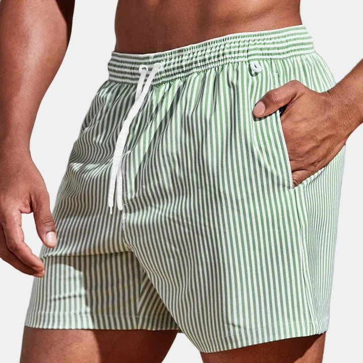 Short à rayures vertes et blanches, main dans la poche latérale, cordon blanc