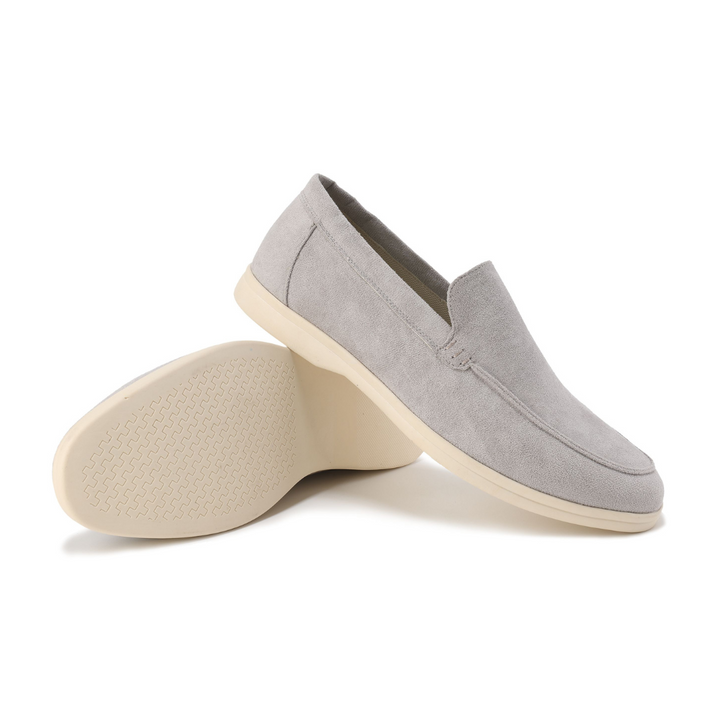Mocassins en daim gris clair, l'un basculé montrant la semelle crème à picots